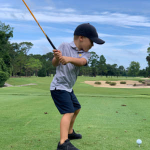 Child teeing off at a golf course